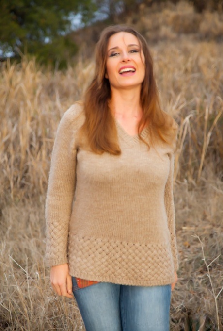 Curvy Vassanta peels off her jeans in a field to show a hairy pussy