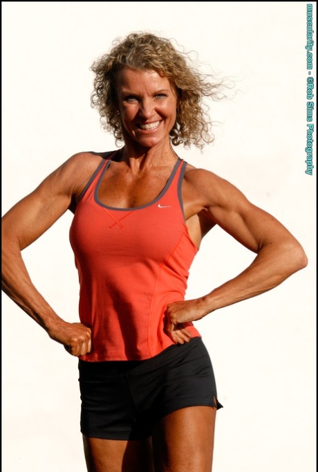 Bodybuilder Denise James flexes at the beach while wearing a bikini