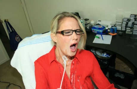 Fully clothed mature blonde in glasses gives a handjob and gets bukkaked