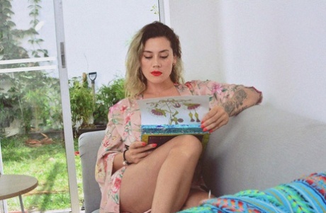 Inked MILF Andrea Garcia exposes her amazing big tits while reading on a couch