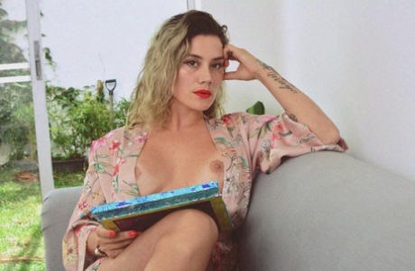 Inked MILF Andrea Garcia exposes her amazing big tits while reading on a couch