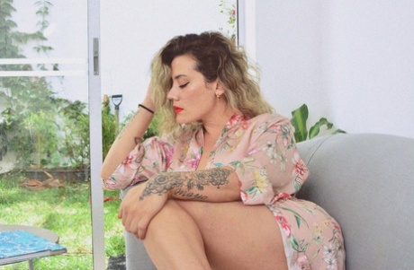 Inked MILF Andrea Garcia exposes her amazing big tits while reading on a couch